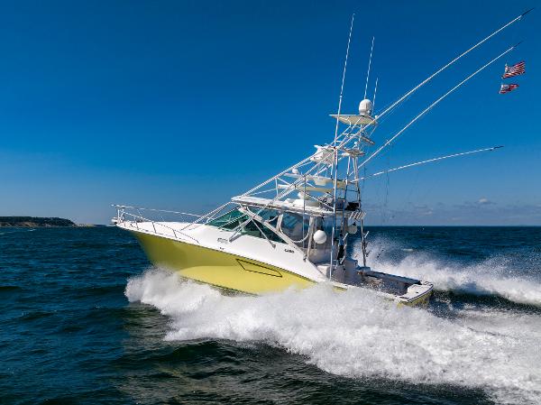 Slide: The Image of 2005 Cabo 40 Express boat cruising on open water under clear blue sky. - 48