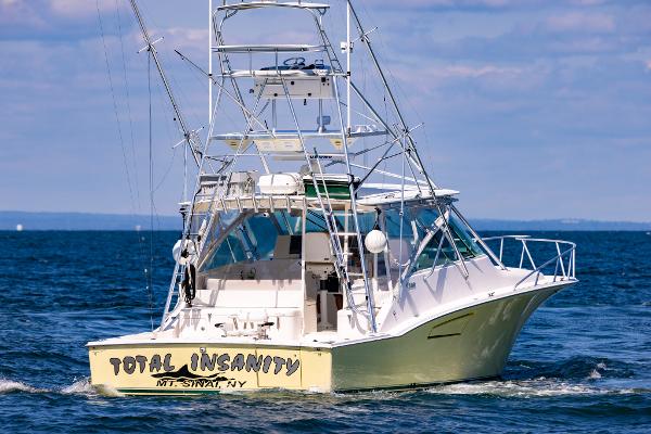 Slide: The Image of 2005 Cabo 40 Express boat named "Total Insanity" on open water. - 6