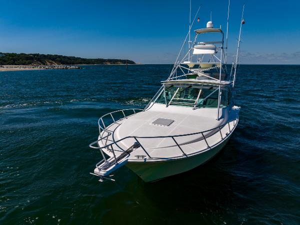 Slide: The Image of 2005 Cabo 40 Express yacht cruising on open water under clear blue skies. - 8