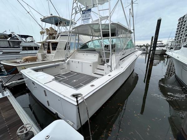 Slide: The Image of 1998 Cabo 45 Express boat docked at a marina, surrounded by other vessels. - 0
