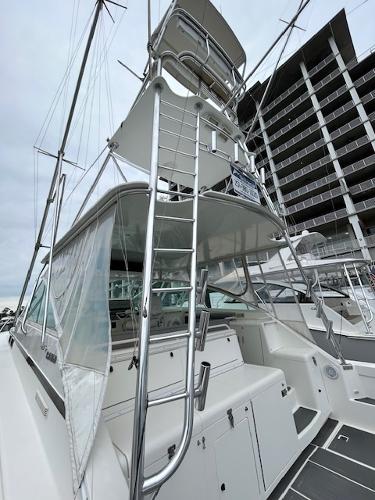 Slide: The Image of 1998 Cabo 45 Express boat with tower ladder and modern marina backdrop. - 2