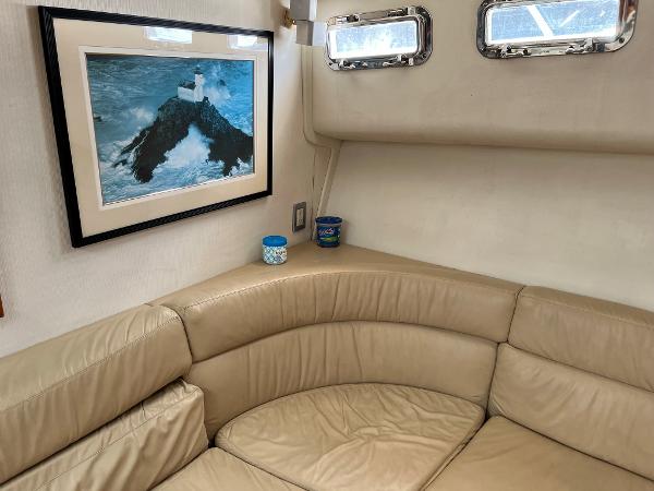 Slide: The Image of Interior of 1998 Cabo 45 Express with beige leather seating and framed ocean artwork. - 20