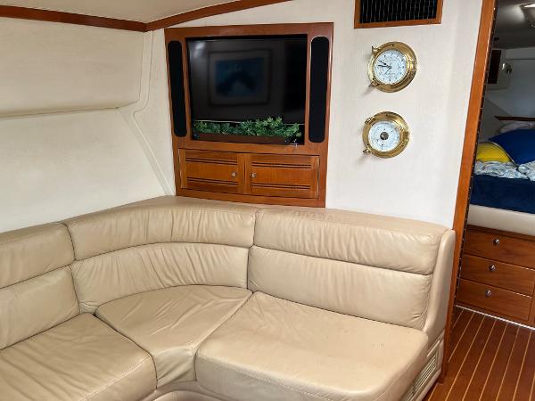 Slide: The Image of 1998 Cabo 45 Express yacht interior with beige leather seating, TV, and nautical decor. - 21