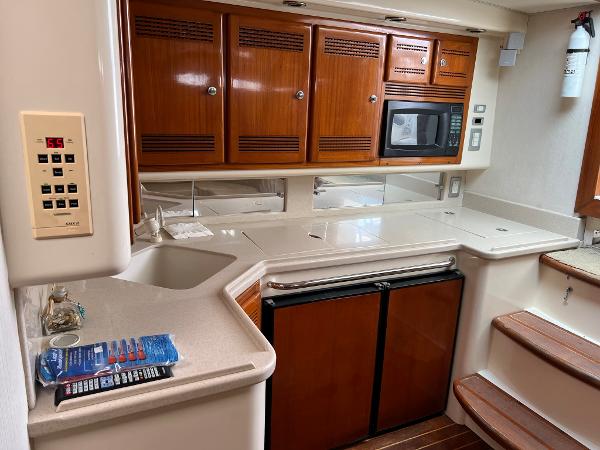 Slide: The Image of 1998 Cabo 45 Express yacht kitchen with microwave, fridge, and wooden cabinets. - 23