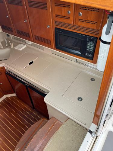 Slide: The Image of 1998 Cabo 45 Express yacht kitchen with microwave, sink, and wooden cabinets. - 32