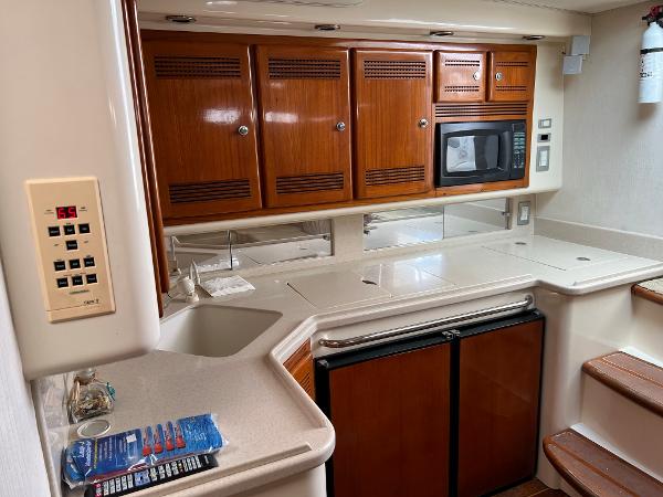 Slide: The Image of 1998 Cabo 45 Express yacht kitchen with wooden cabinets, microwave, and mini-fridge. - 34