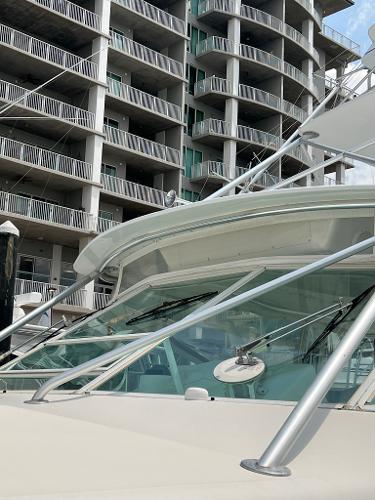 Slide: The Image of 1998 Cabo 45 Express yacht docked near modern apartment buildings. - 4