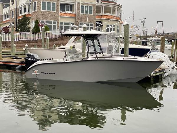 Slide: The Image of 2024 Cape Horn 22 OS boat docked in marina with Suzuki outboard motor. - 0