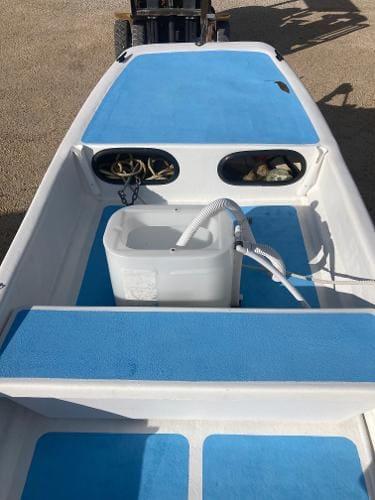 Slide: The Image of 1997 Carolina Skiff 16 DLX boat interior with blue deck padding and storage compartments. - 6