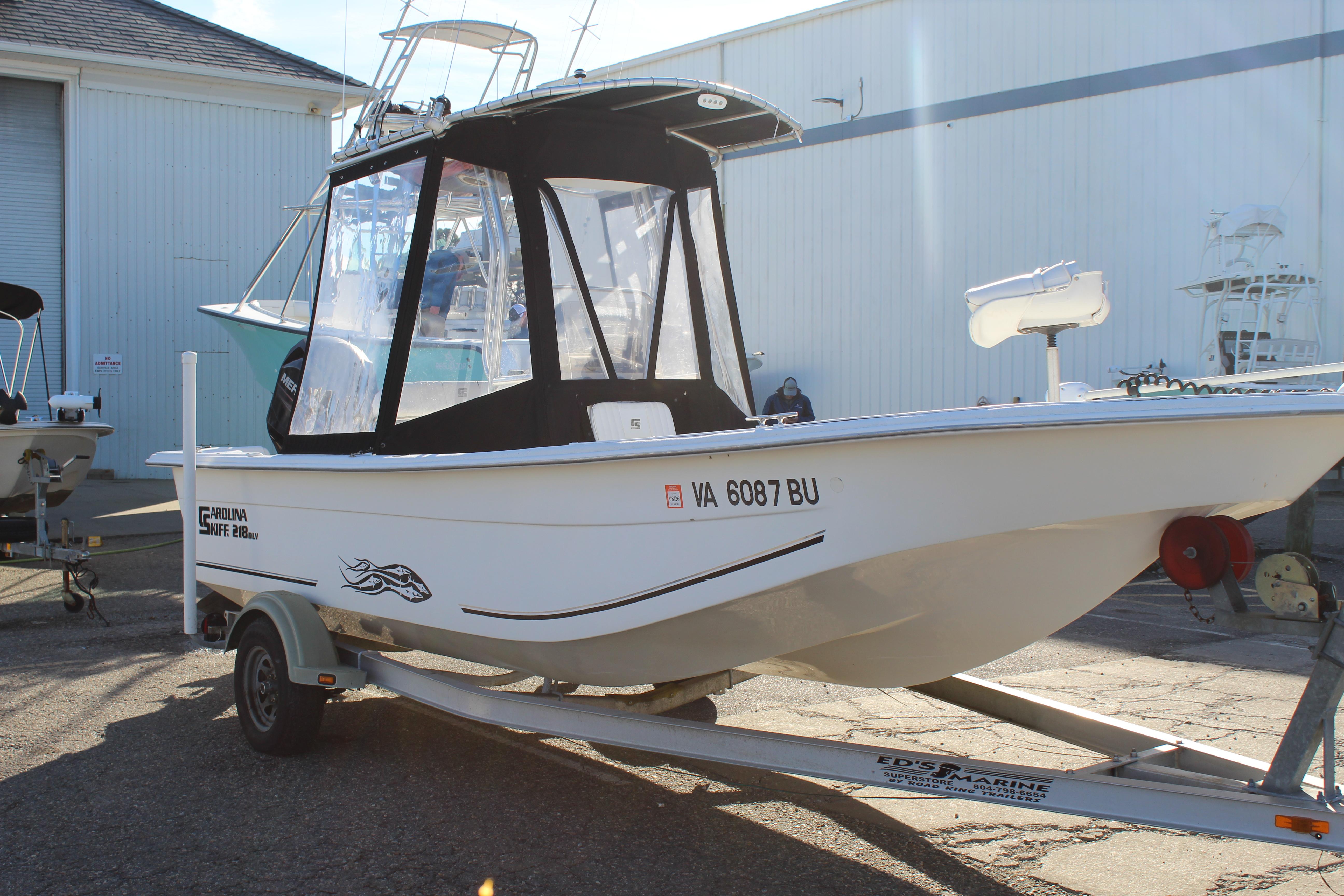 Slide: The Image of 2011 Carolina Skiff 218 DLV boat on trailer, parked outside a warehouse. - 4