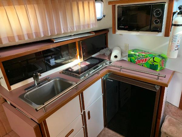 Slide: The Image of 1986 Carver 28 Riviera kitchen with sink, stove, microwave, and fridge. - 12