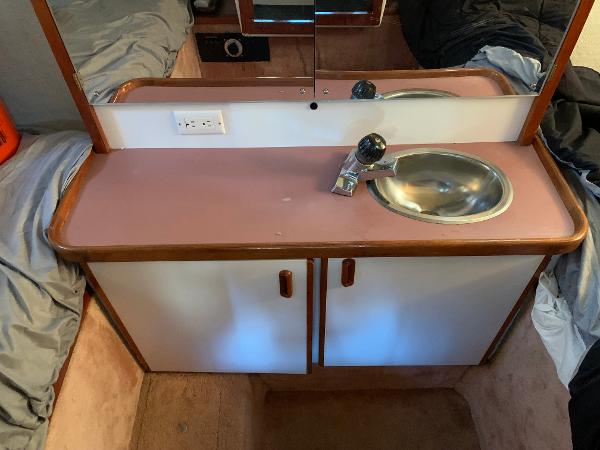 Slide: The Image of 1986 Carver 28 Riviera cabin sink with mirror and storage cabinets. - 9