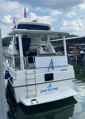 Slide: The Image of 1994 Carver 350 Aft Cabin yacht docked, named "Just In Time," with flags and marina backdrop. - 1