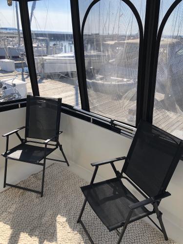 Slide: The Image of 2004 Carver 366 Motor Yacht interior with two black chairs and marina view. - 14