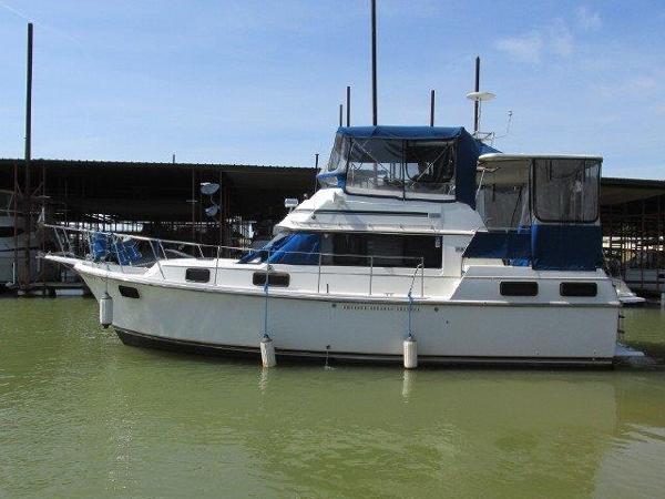 Slide: The Image of 1986 Carver 36 Aft Cabin yacht docked in marina, featuring blue canopy. - 0