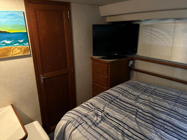 Slide: The Image of 1992 Carver 38 Aft Cabin bedroom with TV, dresser, and striped bedding. - 16