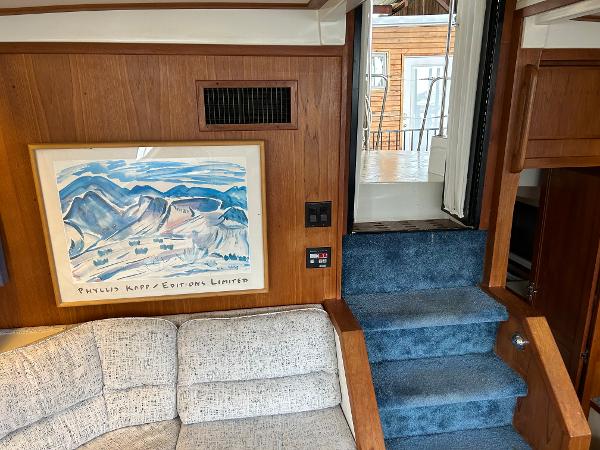 Slide: The Image of Interior of 1992 Carver 38 Aft Cabin with artwork, blue carpeted stairs, and beige sofa. - 18