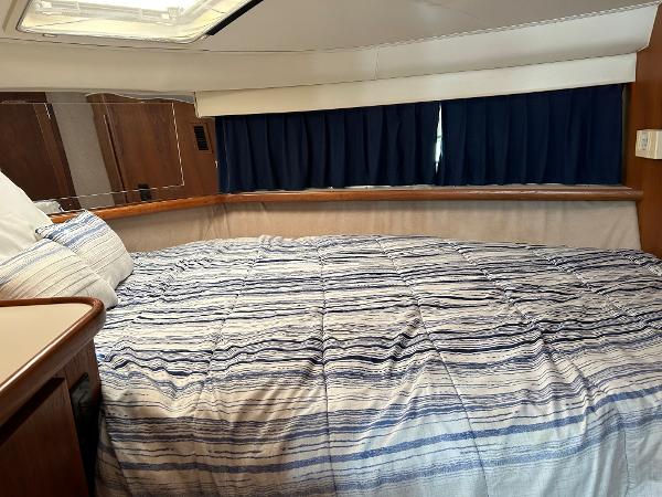 Slide: The Image of 1992 Carver 38 Aft Cabin bedroom with striped bedding and blue curtains. - 48