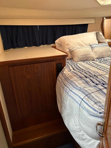 Slide: The Image of 1992 Carver 38 Aft Cabin bedroom with striped bedding and wooden cabinetry. - 49