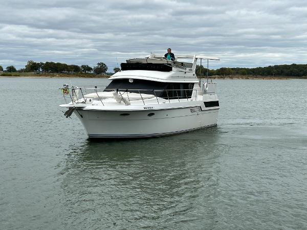 Slide: The Image of 1992 Carver 38 Aft Cabin yacht cruising on a calm lake under cloudy skies. - 5