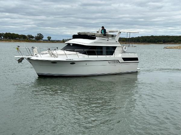 Slide: The Image of 1992 Carver 38 Aft Cabin yacht cruising on a calm lake under cloudy skies. - 6