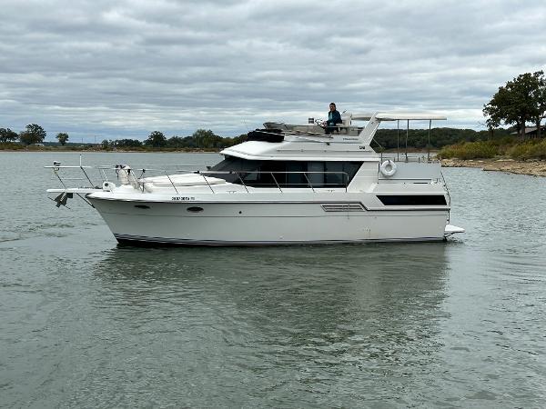 Slide: The Image of 1992 Carver 38 Aft Cabin yacht cruising on a calm lake under cloudy skies. - 7