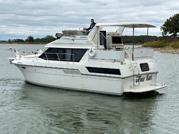Slide: The Image of 1992 Carver 38 Aft Cabin yacht cruising on a calm lake under cloudy skies. - 8