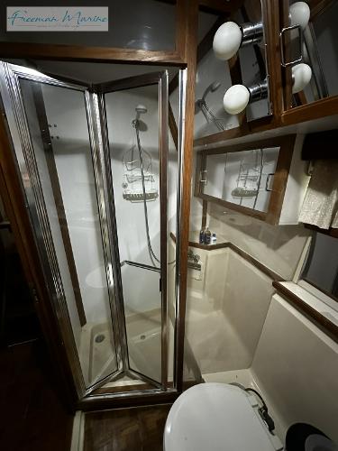 Slide: The Image of 1988 Carver 4207 Aft Cabin bathroom with shower, mirror, and lighting fixtures. - 21