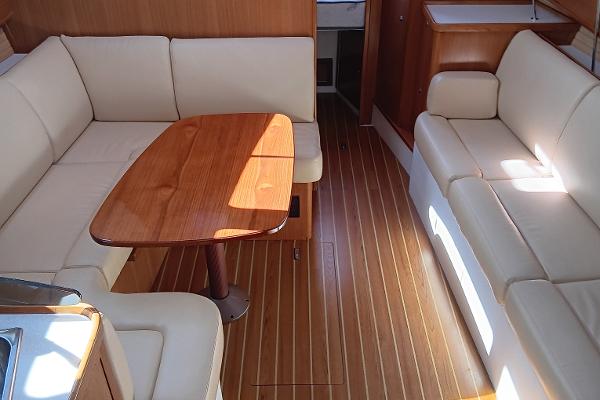 Slide: The Image of Interior of a 2020 Catalina 315 sailboat with white leather seating and wooden table. - 16