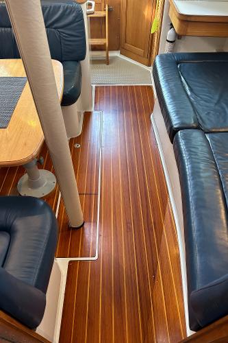 Slide: The Image of Interior of a 2000 Catalina 34 MkII sailboat with polished wood flooring and blue seating. - 13