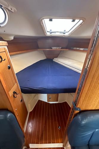 Slide: The Image of Cozy cabin interior of a 2000 Catalina 34 MkII sailboat with wood accents and a blue bed. - 18