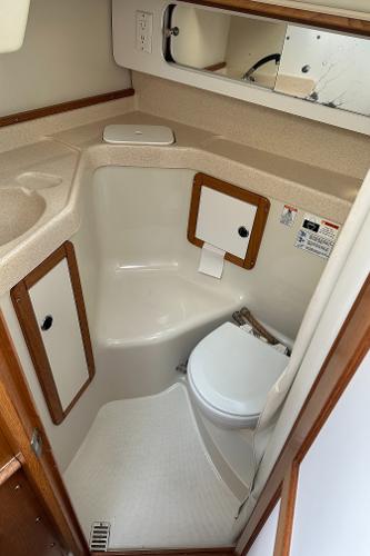 Slide: The Image of 2000 Catalina 34 MkII yacht bathroom with compact design, featuring a toilet, sink, and storage cabinets. - 19