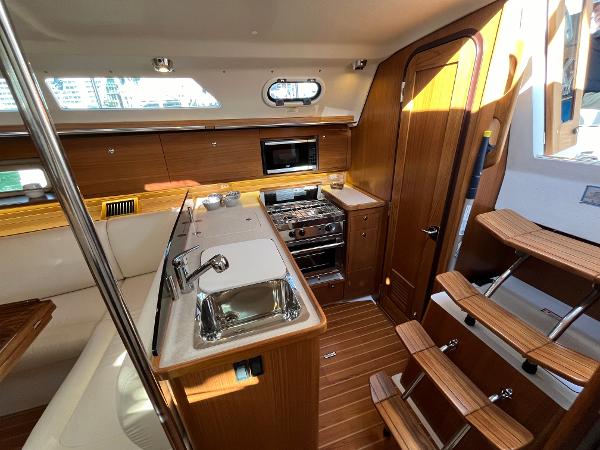 Slide: The Image of Modern kitchen area inside a 2024 Catalina 355 sailboat with wood finishes and stainless steel appliances. - 11