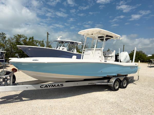 Slide: The Image of 2023 Caymas 26 HB boat on a trailer, light blue hull, parked outdoors. - 1