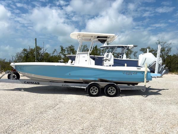 Slide: The Image of 2023 Caymas 26 HB boat on a trailer under a partly cloudy sky. - 2