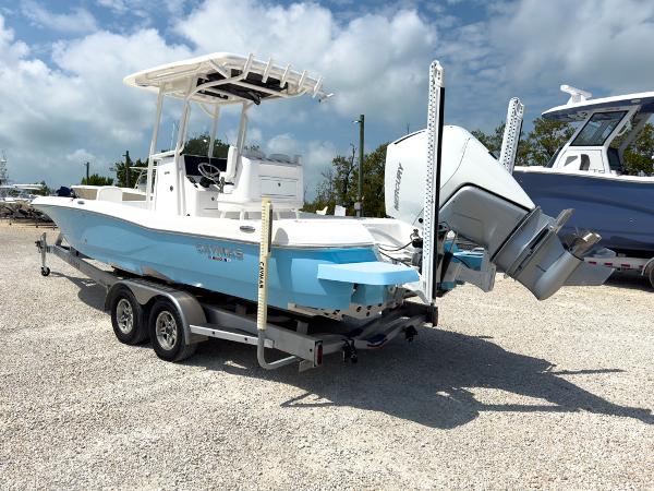 Slide: The Image of 2023 Caymas 26 HB boat on a trailer, white and blue, with outboard motor. - 3