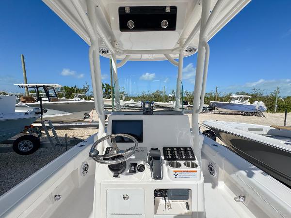 Slide: The Image of 2024 Caymas 26 HB boat cockpit with steering wheel and control panel, docked under clear blue sky. - 13