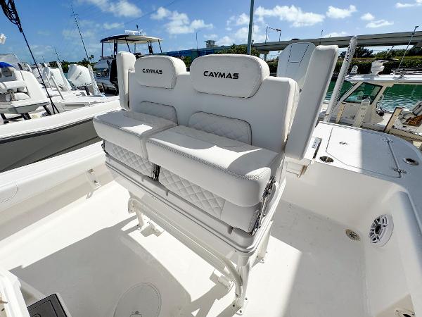 Slide: The Image of 2024 Caymas 26 HB boat with white cushioned seating, docked under a clear blue sky. - 23