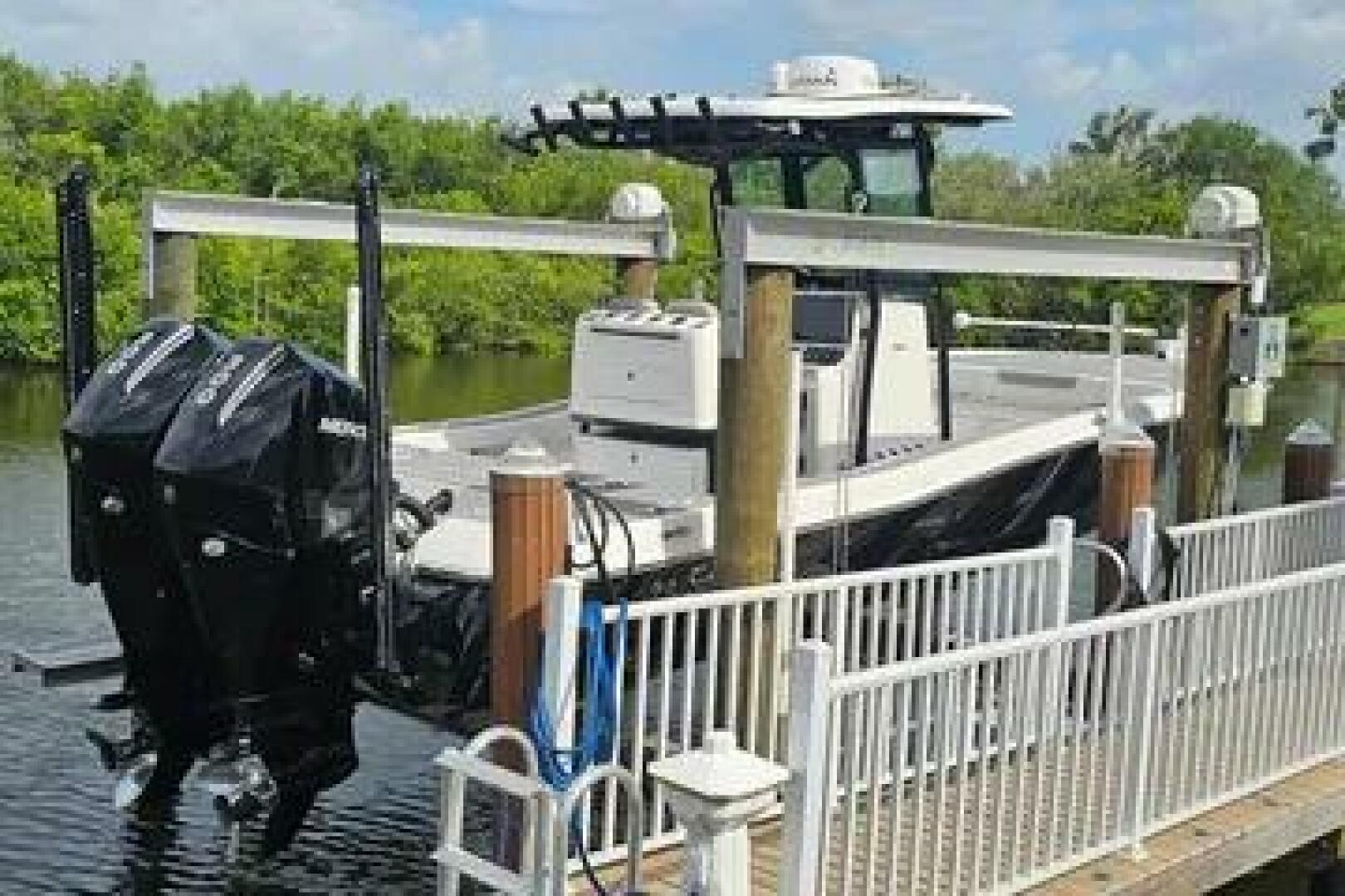 Slide: The Image of 2023 Caymas 28 HB Twin boat docked with dual Mercury engines, surrounded by lush greenery. - 5442596