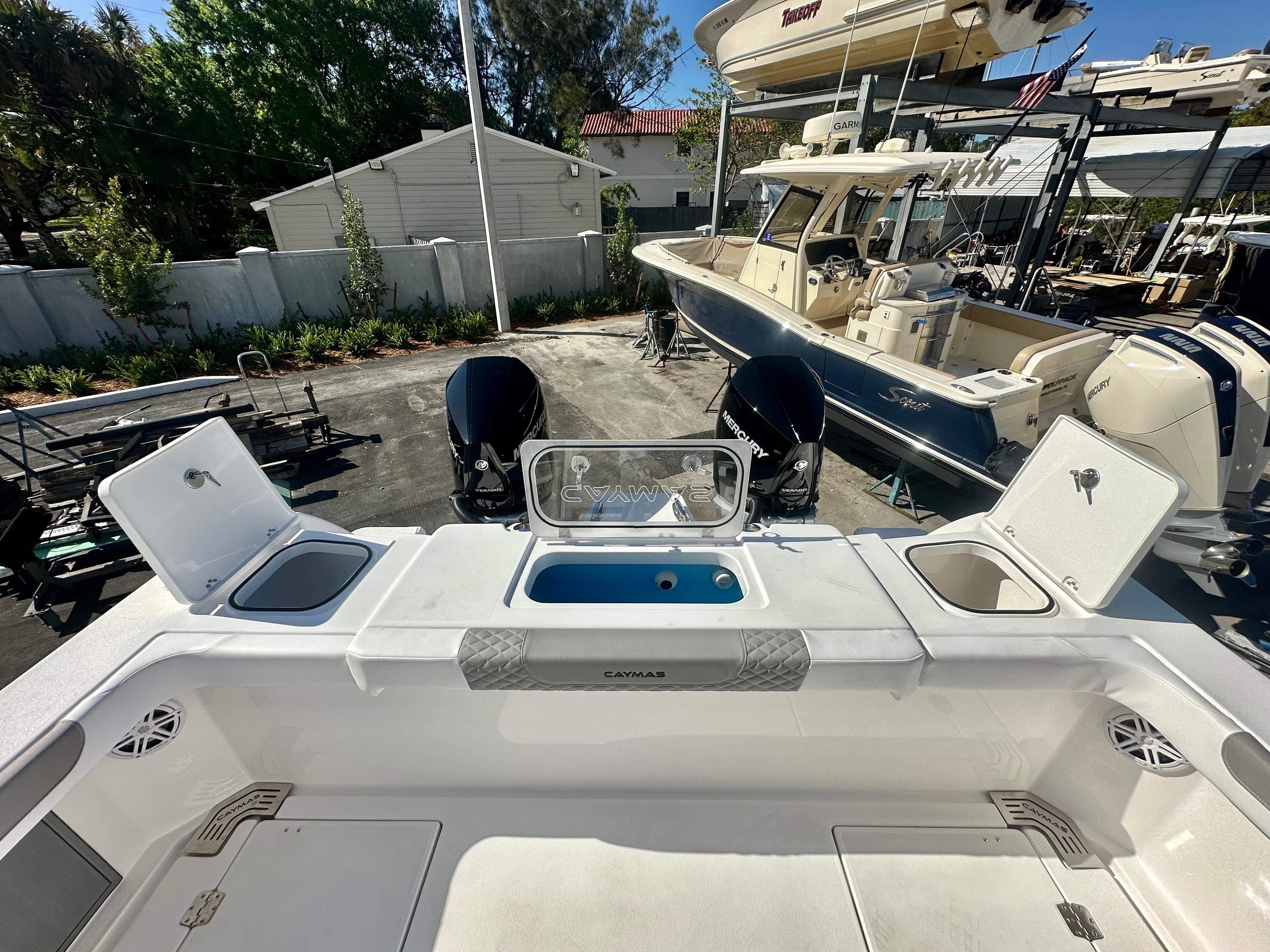 Slide: The Image of 2024 Caymas 30 CT boat with open storage compartments and dual Mercury engines. - 10