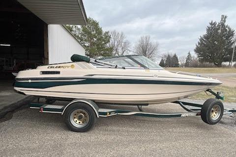 Slide: The Image of 1995 Celebrity 180 Bowrider boat on trailer, parked outdoors near a building. - 0