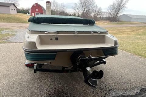 Slide: The Image of 1995 Celebrity 180 Bowrider boat on trailer, parked outdoors near barns and trees. - 2