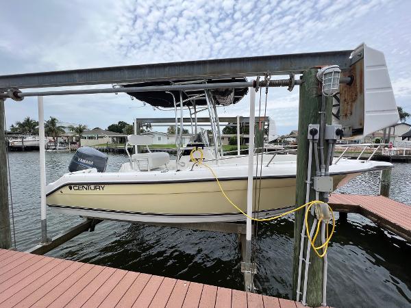 Slide: The Image of 2004 Century 2000 Center Console boat docked on lift by waterfront homes. - 1