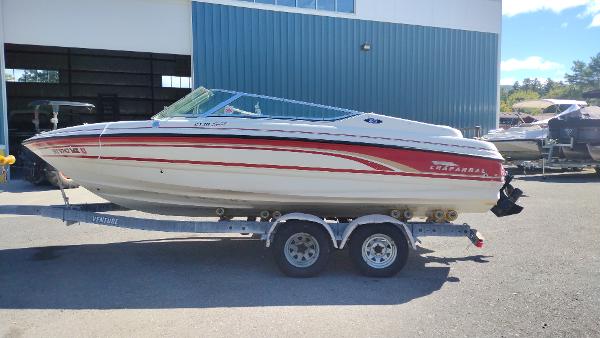 Slide: The Image of 1999 Chaparral 2130 SS boat on trailer, parked outdoors near a blue building. - 1