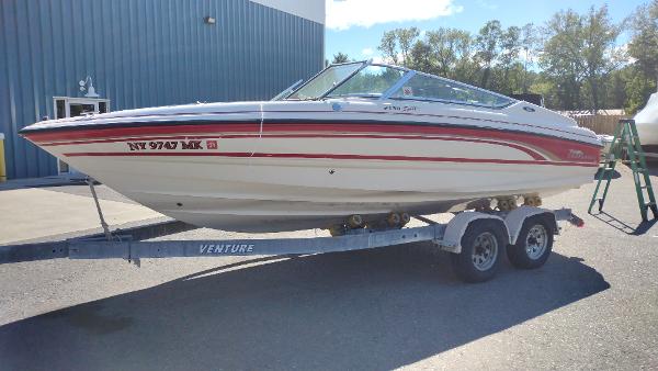 Slide: The Image of 1999 Chaparral 2130 SS boat on trailer, parked outdoors near a blue building. - 2