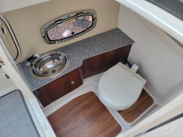 Slide: The Image of 2018 Chaparral 257 SSX boat bathroom with sink, toilet, and wood flooring. - 11