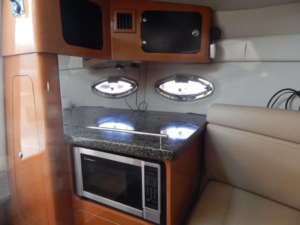 Slide: The Image of 2009 Chaparral 275 SSi boat interior with kitchenette, featuring microwave and porthole windows. - 19