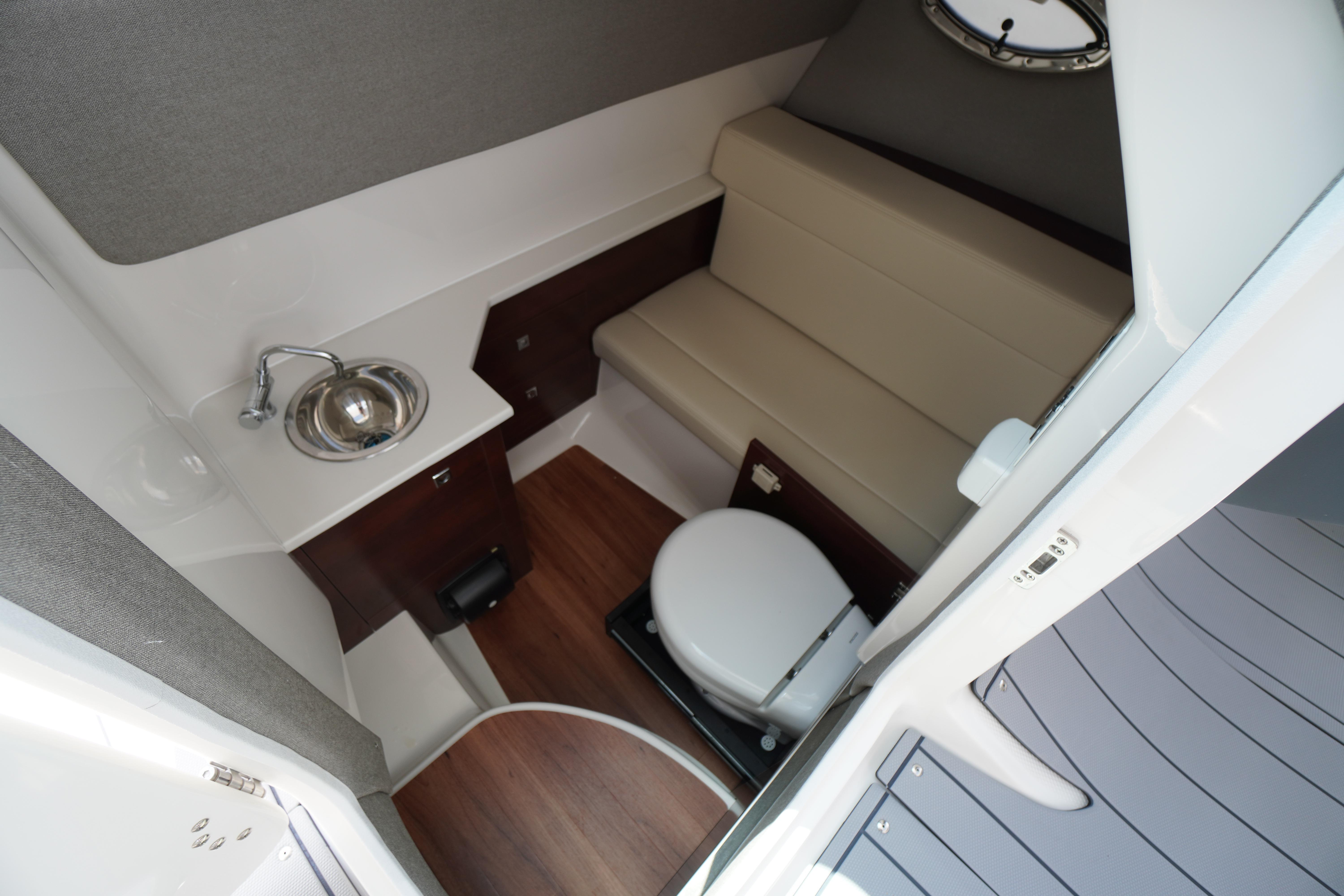 Slide: The Image of 2025 Chaparral 280 OSX boat interior with sink, toilet, and seating area. - 28