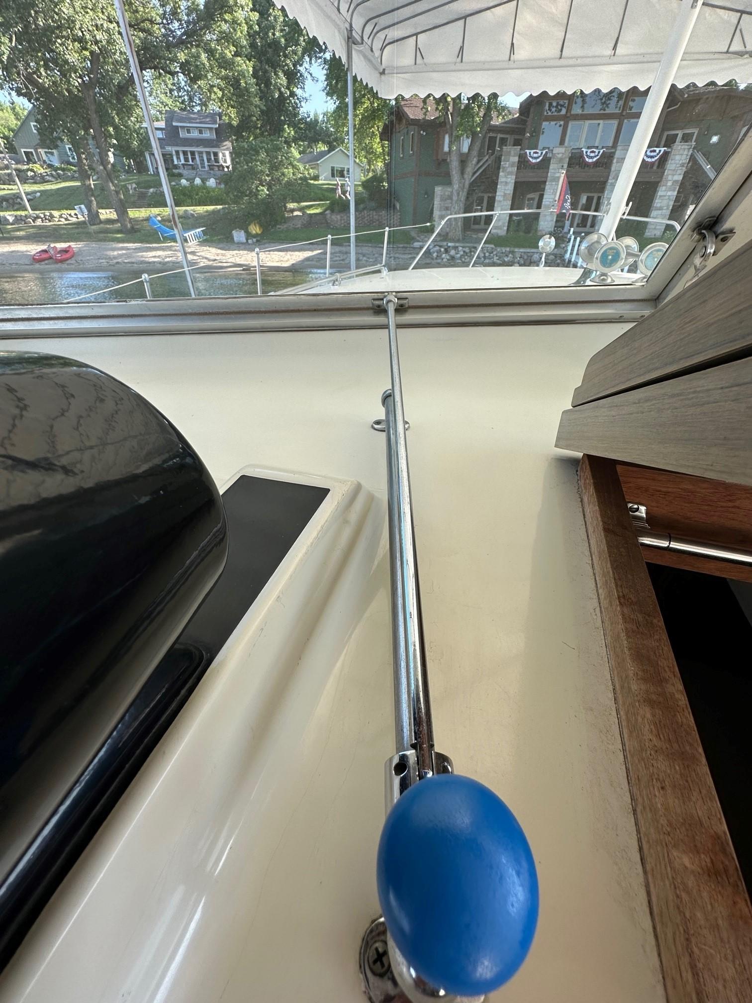 Slide: The Image of 1968 Chris-Craft 35 Commander boat control lever with blue knob, docked near waterfront homes. - 18