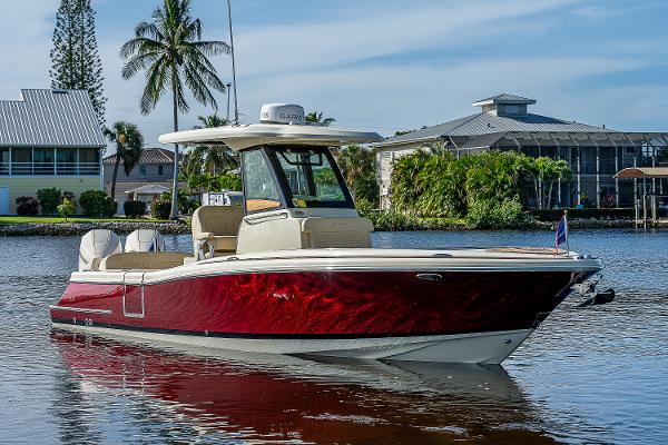 Slide: The Image of 2019 Chris-Craft Catalina 27 boat with red hull, docked near waterfront homes. - 1